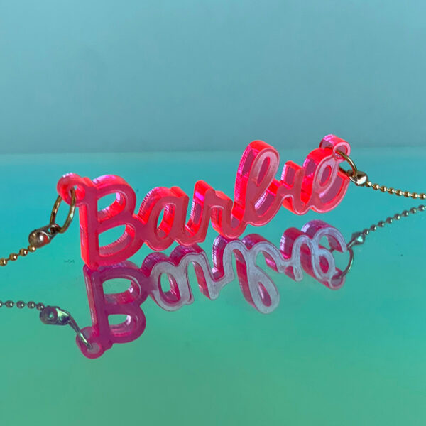 goudkleurige ketting met een doorzichtig fel roze hanger die barbie zegt